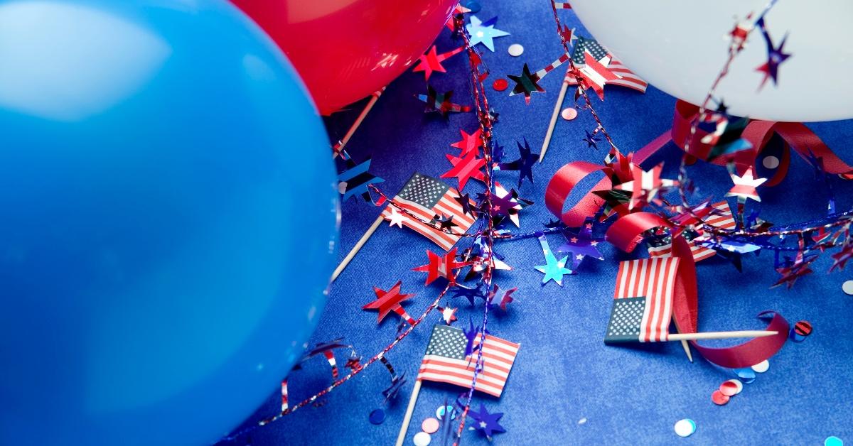 Blue background with Fourth of July balloons and American flags. 