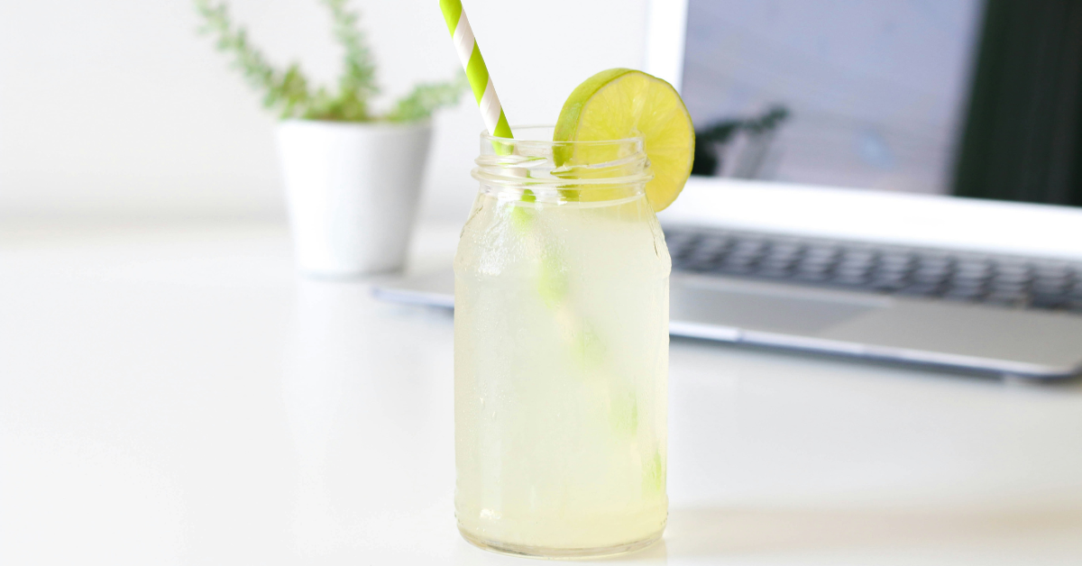 A frosty glass of lemonade sits in front of a computer laptop